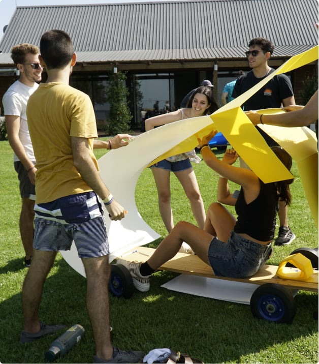 Team of developers playing and assembling a cardboard car.
